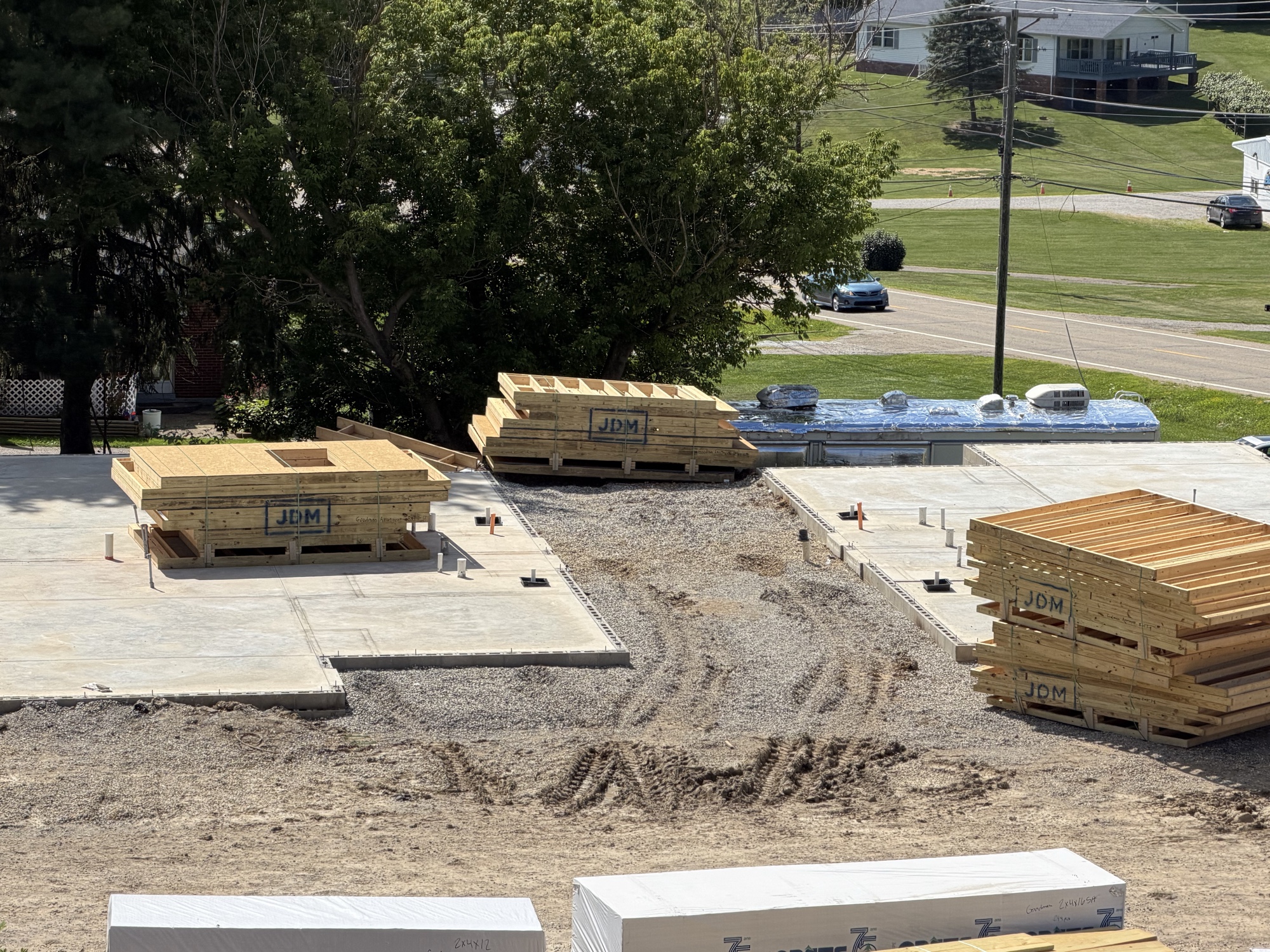 Real construction photo: prefabricated floor truss bundles staged on the finished slabs at The Legacy at Richland Commons, ready for framing installation, July 30, 2026