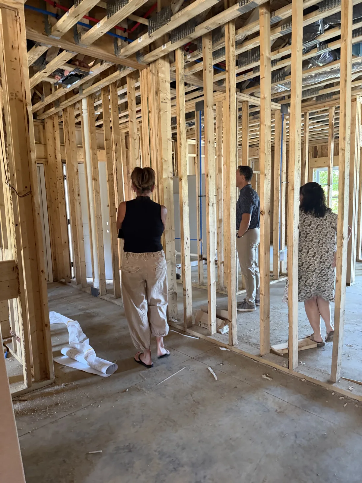 Real construction photo: project team conducting an interior walkthrough among framed walls and overhead utility rough-ins at The Legacy at Richland Commons, September 8, 2026