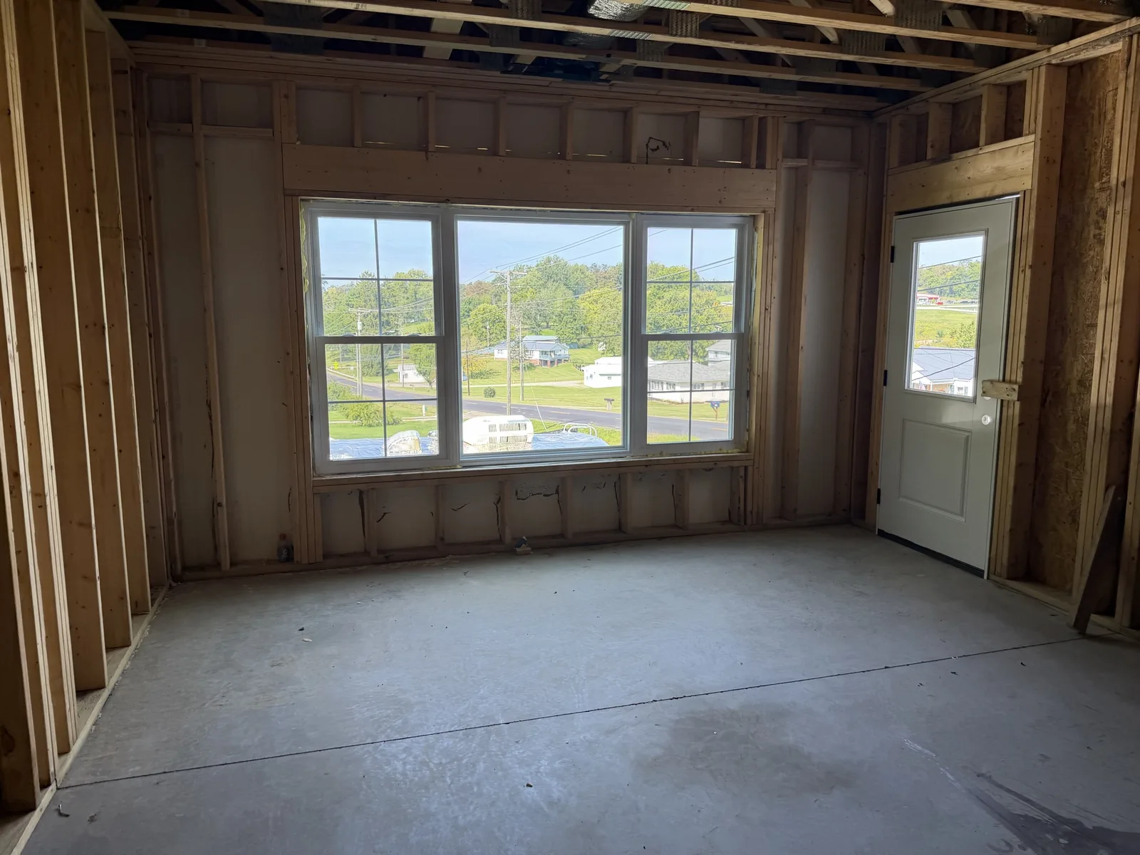 Real construction photo: framed apartment room with installed windows and exterior door at The Legacy at Richland Commons, September 8, 2026