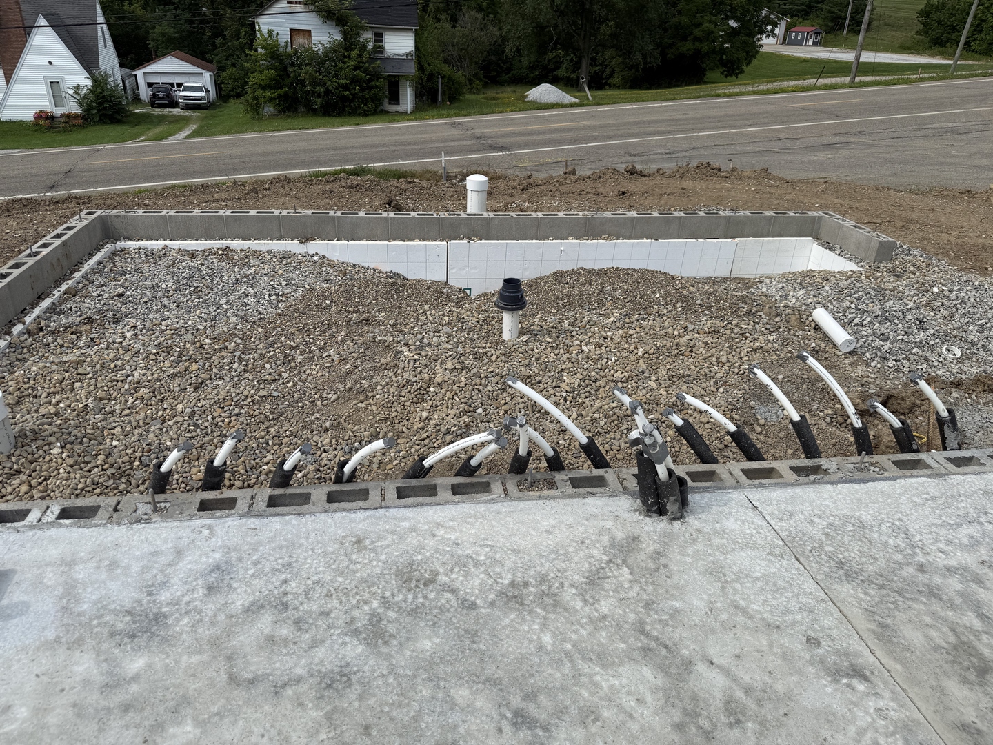 Real construction photo: electrical conduit rough-in emerging from the slab edge at The Legacy at Richland Commons, July 2026