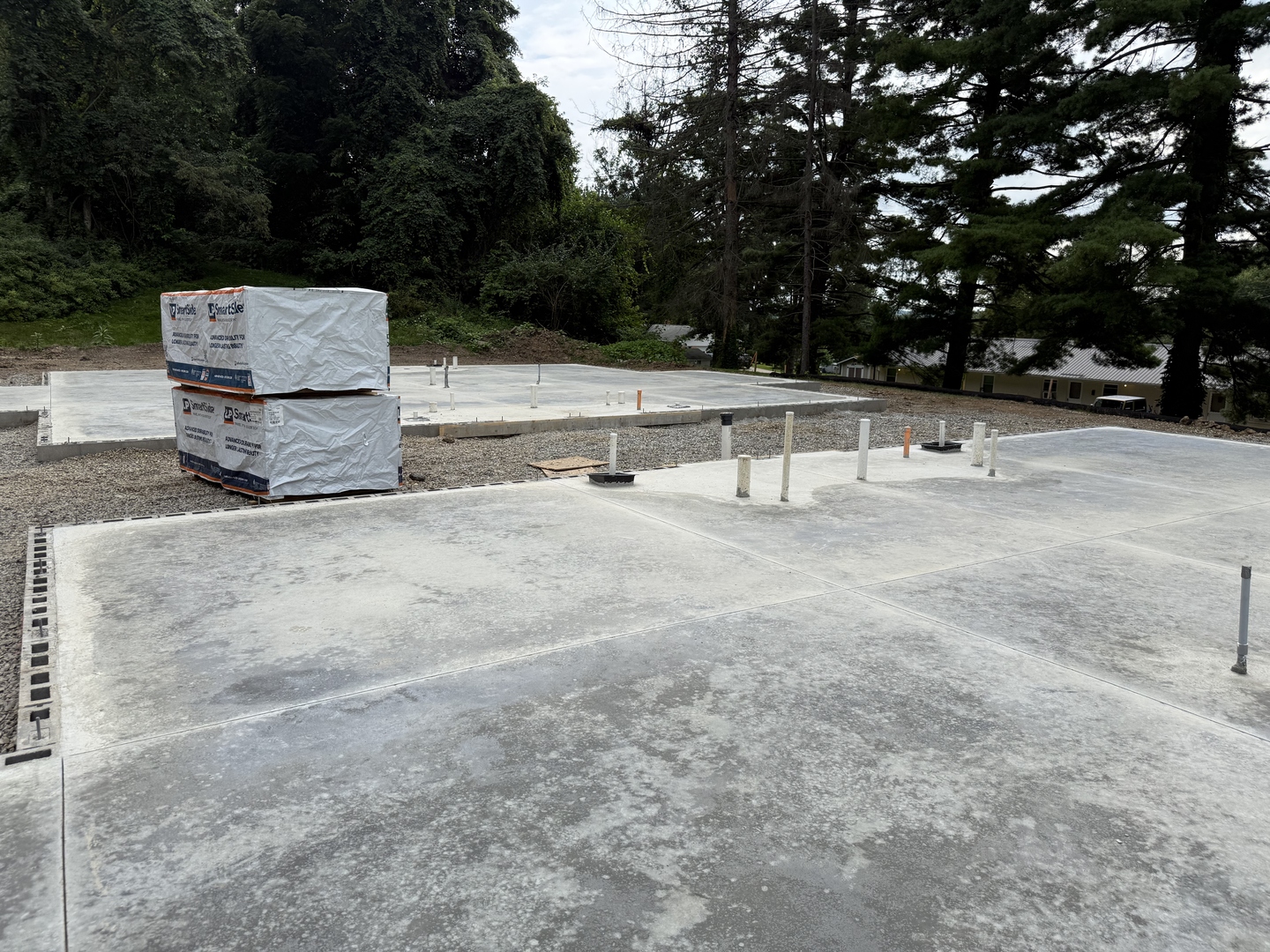 Real construction photo: finished concrete slabs with building materials staged on site at The Legacy at Richland Commons, July 2026
